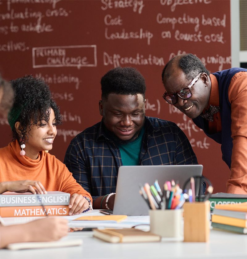 smiling-black-teacher-helping-students-working-on-2025-03-18-22-10-30-utc